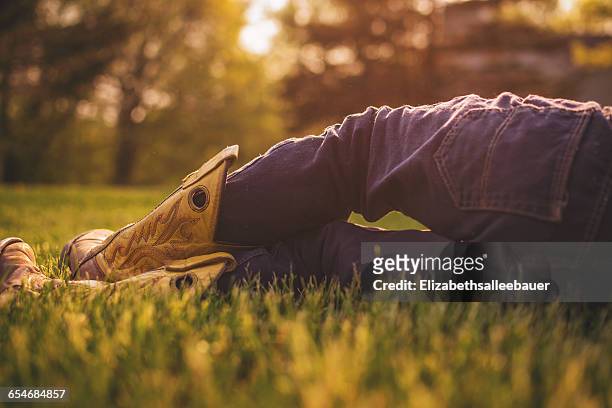boy wearing cowboy boots lying on grass - cowboy sleeping stock pictures, royalty-free photos & images