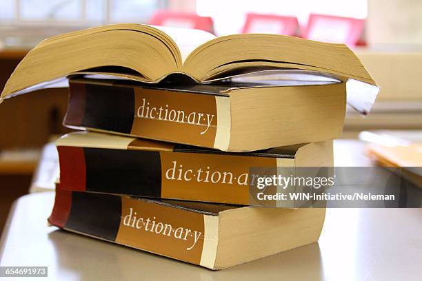 stack of dictionaries on a desk - dictionary stock pictures, royalty-free photos & images