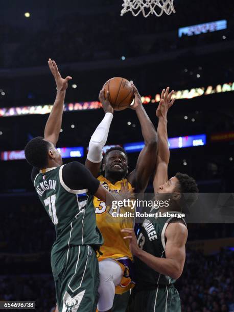 Julius Randle of the Los Angeles Lakers attempts a shot against John Henson Malcolm Brogdon of the Milwaukee Bucks on March 17, 2017 at STAPLES...