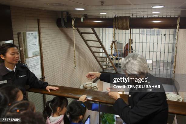 Nooses are seen past a prison cell as a Correctional Services Department officer , clad in a historical uniform and wig, demonstrates the action of...