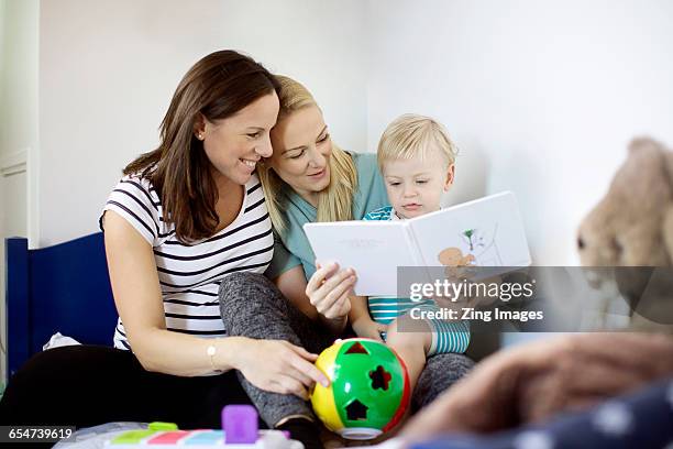 female couple reading with baby boy - lesbiana fotografías e imágenes de stock