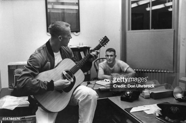 American military cadet and football player Pete Dawkins, of the Army Cadets team, plays guitar as his roommate, Lee Nunn, watches, in a room at the...