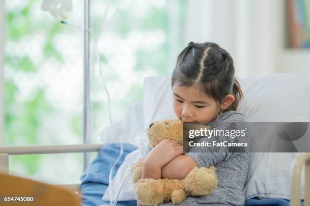 little girl holding her teddy bear - sad child hospital stock pictures, royalty-free photos & images