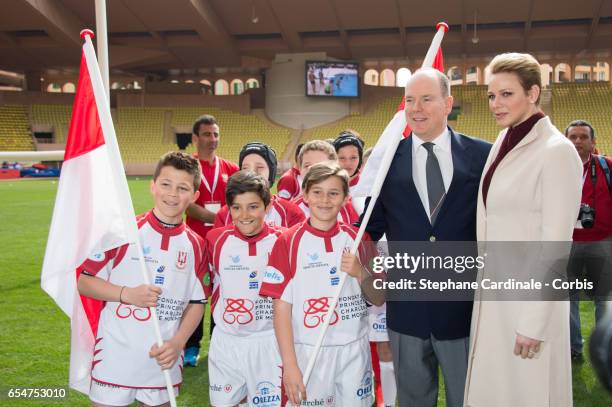 Prince Albert II of Monaco and Princess Charlene of Monaco pose with the Monaco Team during the Sainte Devote Rugby Tournament on March 18, 2017 in...