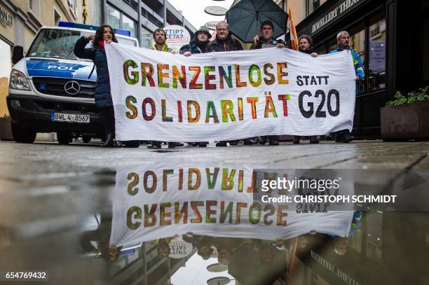 Demonstrators with a banner reading 'solidarity without borders instead of G20' protest on the sidelines of the G20 Finance Ministers and Central...