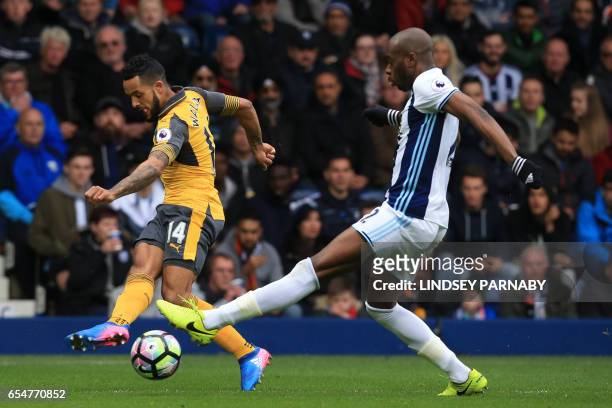 Arsenal's English midfielder Theo Walcott has a shot blocked by West Bromwich Albion's French-born Cameroonian defender Allan Nyom during the English...