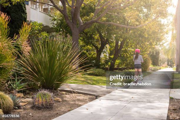 little girl pushing her scooter along a sidewalk - california suburb stock pictures, royalty-free photos & images