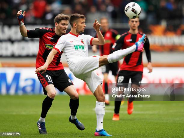 Moritz Leitner of Augsburg is challenged by Lukas Kuebler of Freiburg during the Bundesliga match between FC Augsburg and SC Freiburg at WWK Arena on...