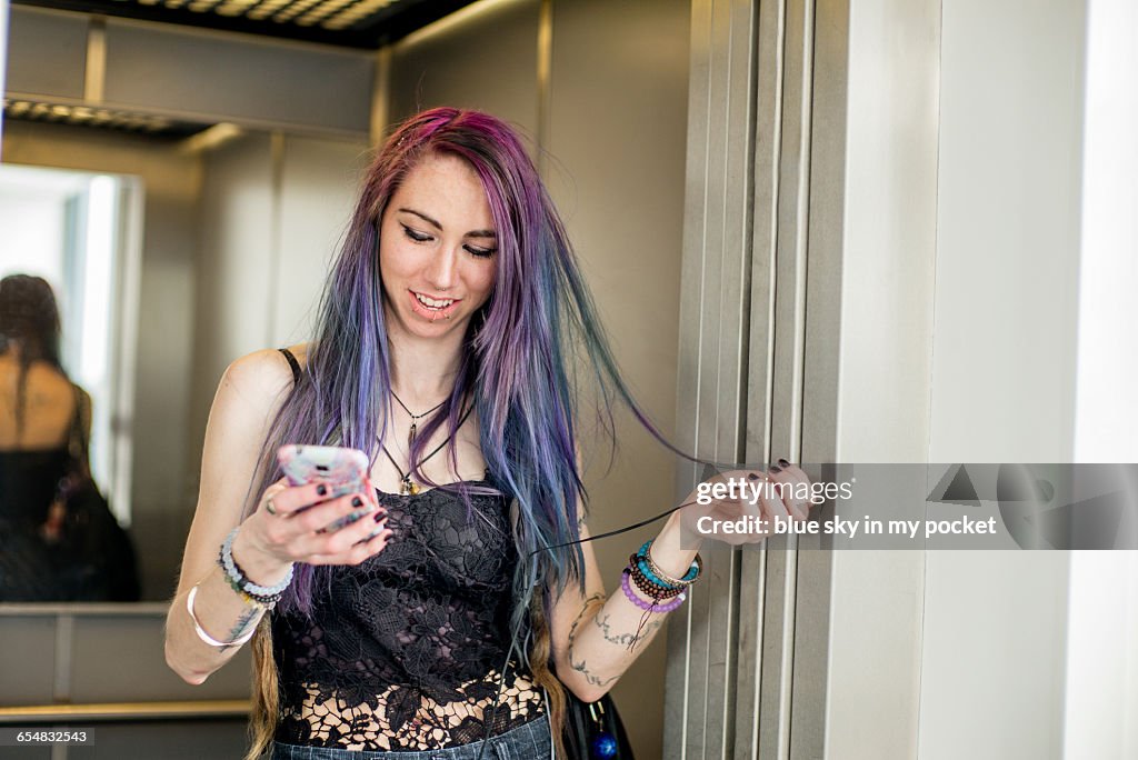 A young woman with purple hair in an elivator