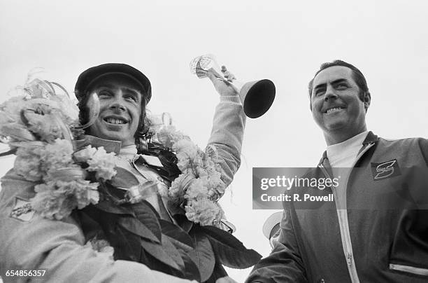 Australian racing driver Jack Brabham , founder of the Brabham racing team, with Scottish racing driver Jackie Stewart , who has just won the British...