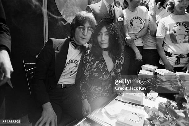 Singer and songwriterJohn Lennon with his wife Yoko Ono, signing copies of her conceptual art book 'Grapefruit' at Selfridges, London, 15th July 1971.