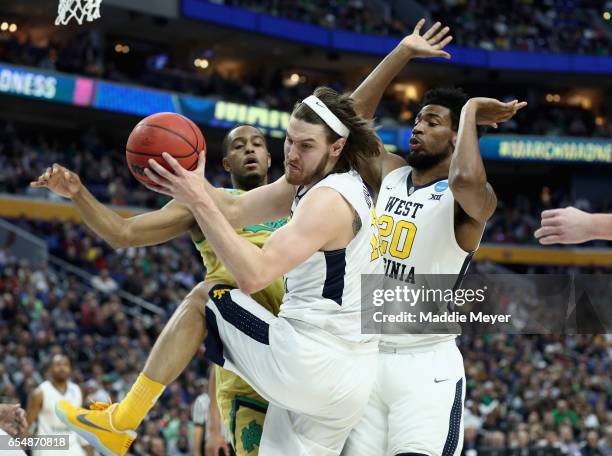 Teammates Nathan Adrian and James Bolden of the West Virginia Mountaineers battle for a loose ball against V.J. Beachem of the Notre Dame Fighting...