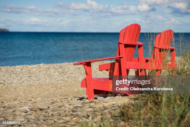 red muskoka chairs on the banks of the georgian bay. - canada day stock pictures, royalty-free photos & images