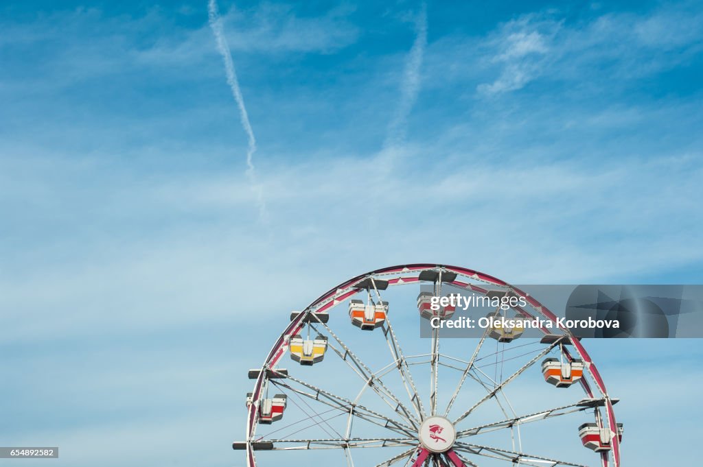 Vintage colorful ferris wheel against a sunny blue sky.