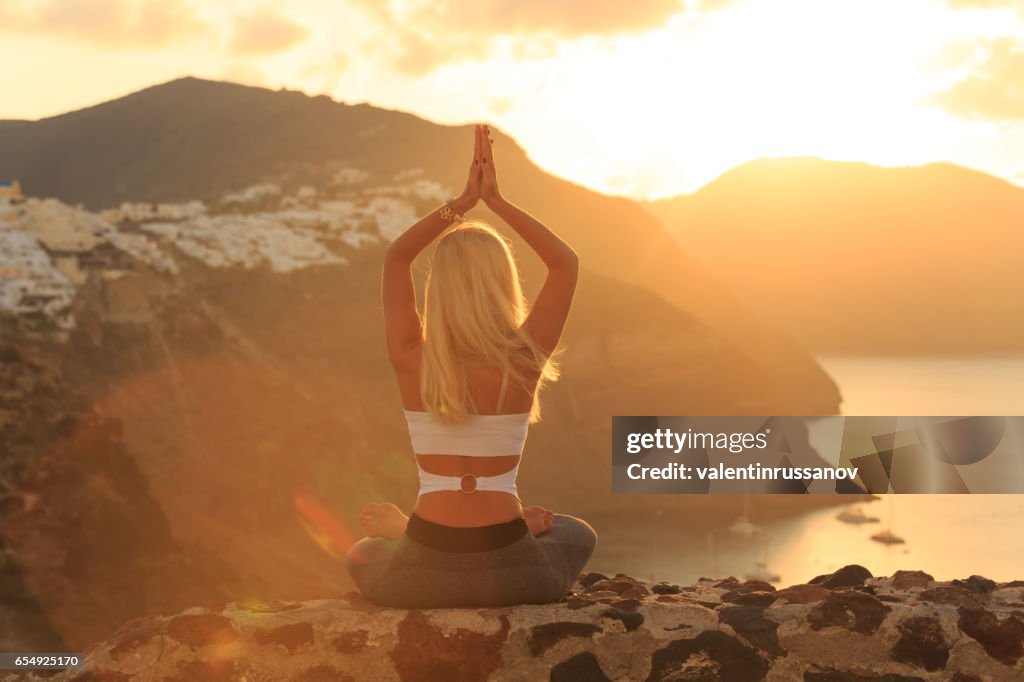 Rear view of blond woman practicing yoga in Santorini