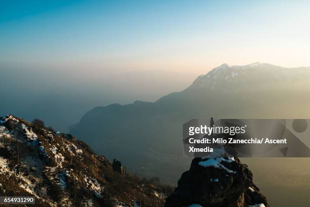female hiker stands on mountain summit, looks off - schweizer berge stock-fotos und bilder