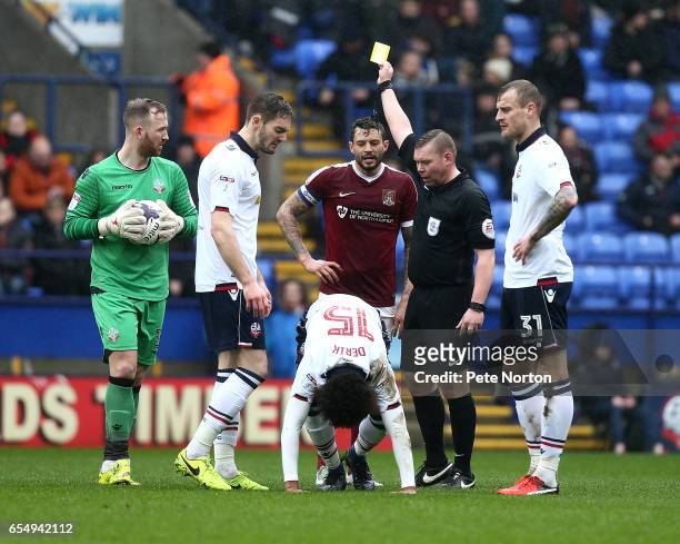 Referee Richard Smith shows a Yellow card to Marc Richards of Northampton Town after a foul on Derik Osede of Bolton Wanderers as his team mates Ben...