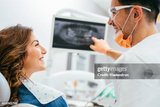 dentist showing a patient her x-ray - dentista imagens e fotografias de stock