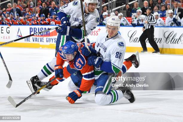 Connor McDavid of the Edmonton Oilers gets tangled up with Nikita Tryamkin of the Vancouver Canucks on March 18, 2017 at Rogers Place in Edmonton,...
