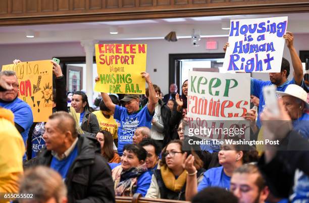 Community members hold signs as Mayor Muriel Bowser speaks at the More For Housing Now rally at the Foundry United Methodist Church in Washington, DC...