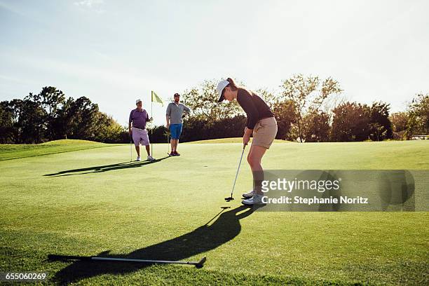 woman putting on golf course with family watching - golf accessories stock pictures, royalty-free photos & images