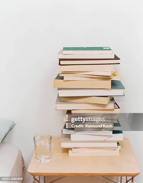 stack of books on night table - libro en rústica fotografías e imágenes de stock