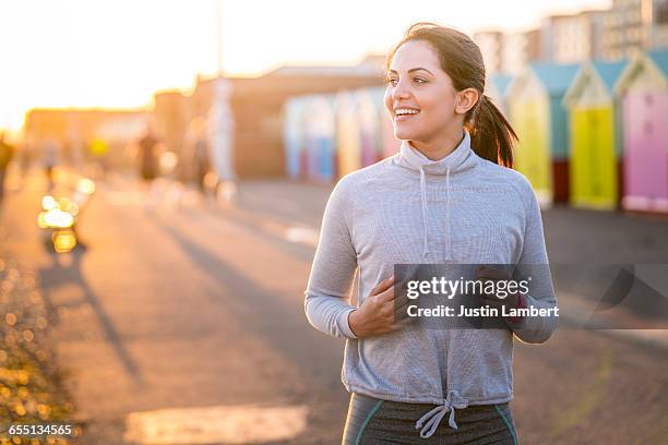 woman running along beachfront - active woman photos et images de collection