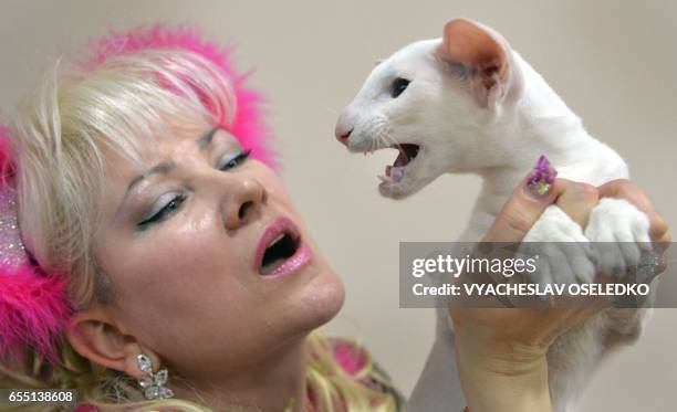 An owner poses with her Oriental Shorthair cat during the International cat exhibition in Bishkek on March 19, 2017. Cat lovers from Kyrgyzstan,...