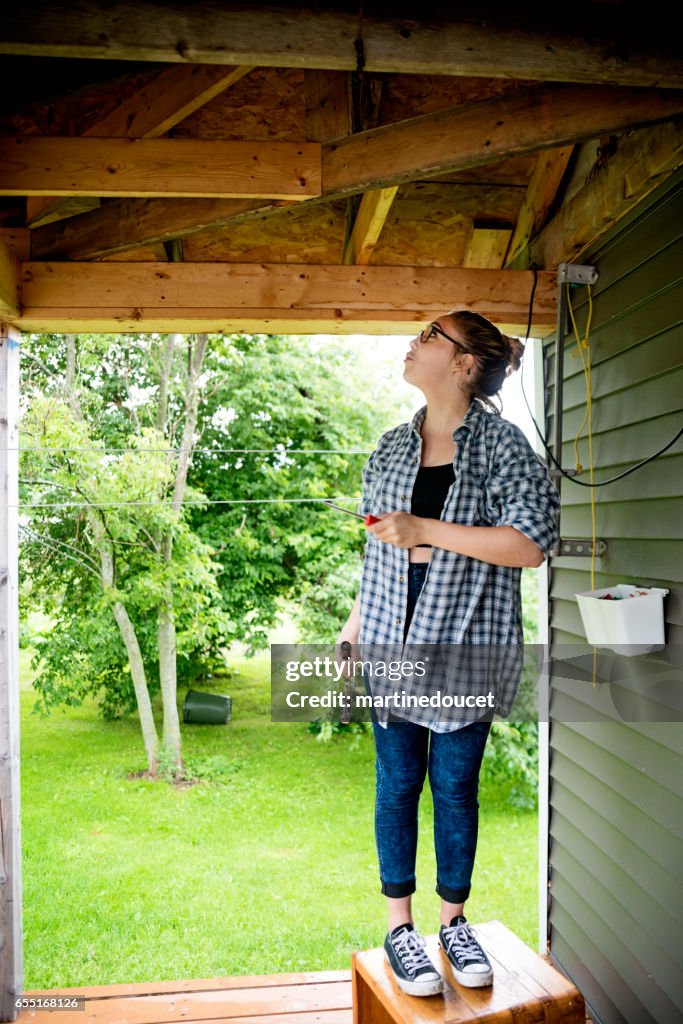 Young woman doing some DIY around the house outdoors.