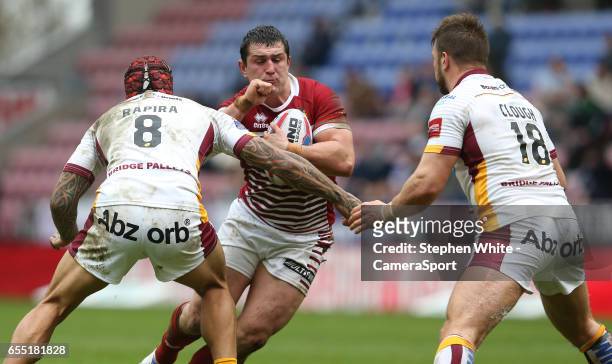 Wigan Warriors' Ben Flower is tackled by Huddersfield Giants' Sam Rapira and Paul Clough during the Betfred Super League Round 5 match between Wigan...