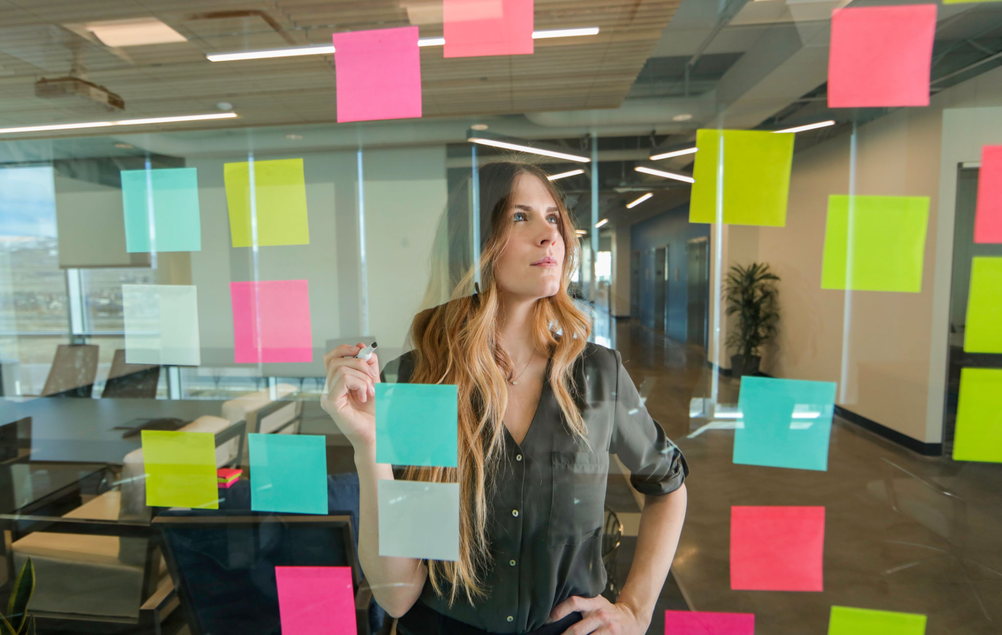 Woman using sticky notes on glass wall Woman using sticky notes on glass wall