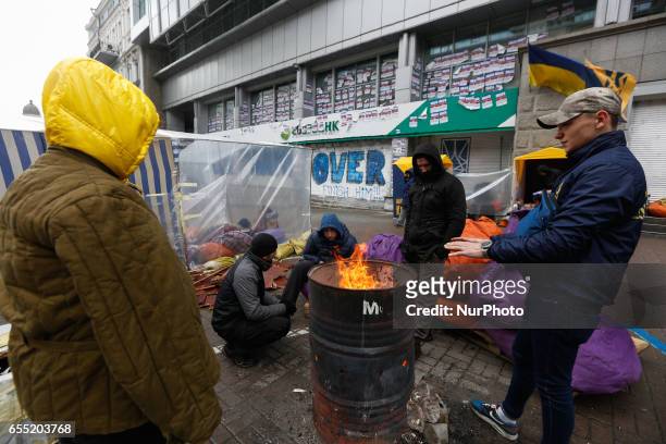 Activists blocking Sberbank branch warm themselves around firepit set next to a financial institution in Kyiv, Ukraine, March 19, 2017. Supporters...