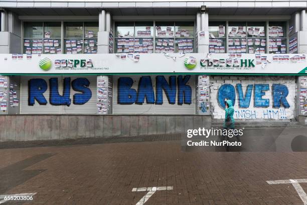 Woman passes by a graffiti-covered blocked Sberbank branch in Kyiv, Ukraine, March 19, 2017. Supporters and members of Azov nationalistic battalion's...