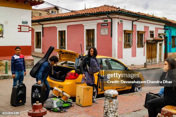 bogotá, colombia - a group of local musicians seen moving their equipment using a taxi just of chorro de quevedo in the historic la candelaria district - plaza del chorro de quevedo stock pictures, royalty-free photos & images
