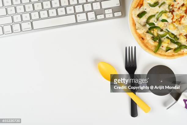 office table top view with pizza, computer keyboard, spoon, fork, pizza cutter - pizzaskärare bildbanksfoton och bilder
