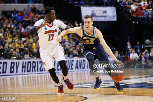 Duncan Robinson of the Michigan Wolverines drives against Mangok Mathiang of the Louisville Cardinals in the first half during the second round of...