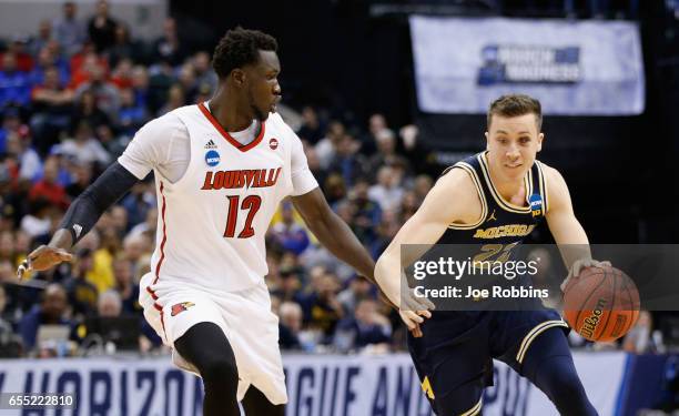 Duncan Robinson of the Michigan Wolverines drives against Mangok Mathiang of the Louisville Cardinals in the first half during the second round of...