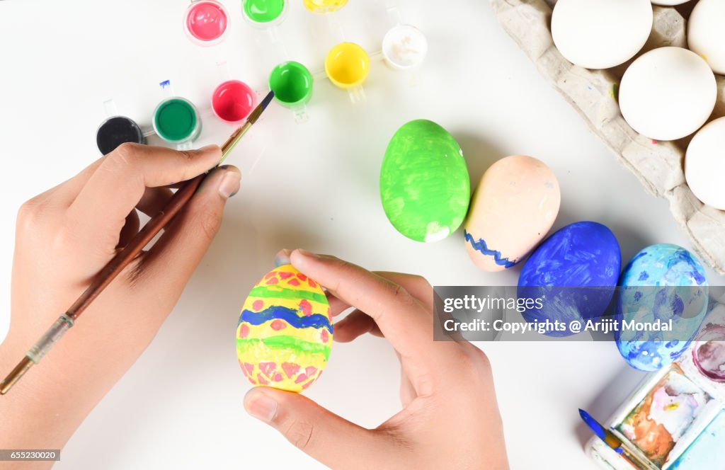 Young Boy Colouring Easter Eggs with Paintbrush Top View