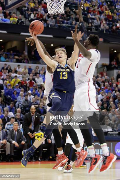 Moritz Wagner of the Michigan Wolverines shoots against Mangok Mathiang of the Louisville Cardinals in the second half during the second round of the...