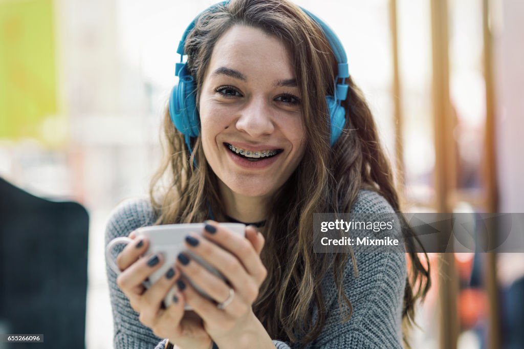 Girl smiling to the camera and holding a cup of tea or coffee