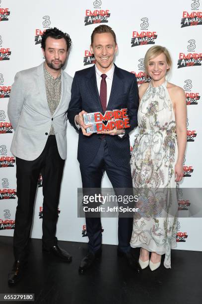 Tom Hiddleston poses in the winners room with his two awards for Empire Hero and Best TV Series for The Night Manager with presenters Anne-Marie Duff...