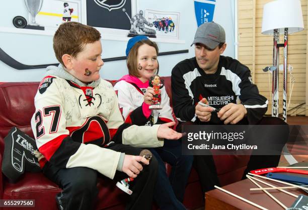Two young fans with bobble heads chat with former Ottawa Senators Chris Phillips at the Mitsubishi Electric activation tent installation at NHL...