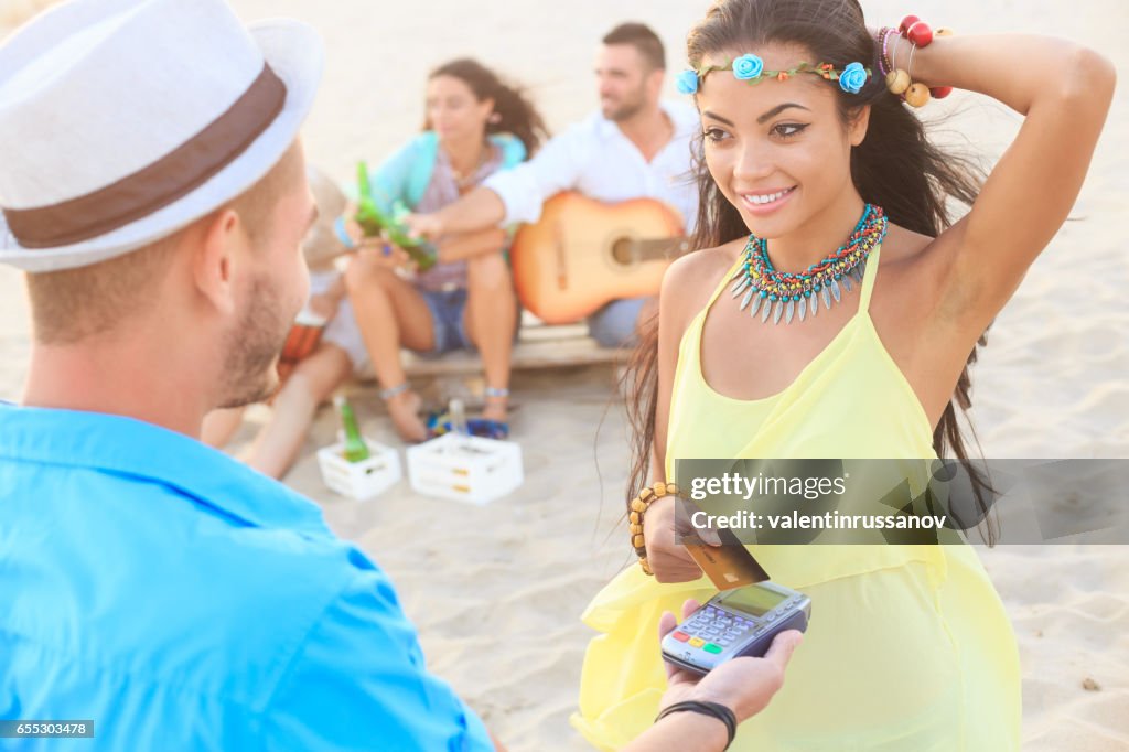 Hermosa mujer joven con tarjeta de crédito para el pago sin contacto en la playa