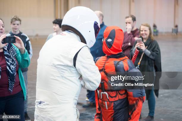 Deadpool cosplayer interacts with The Stig during the MCM Birmingham Comic Con at NEC Arena on March 19, 2017 in Birmingham, England.