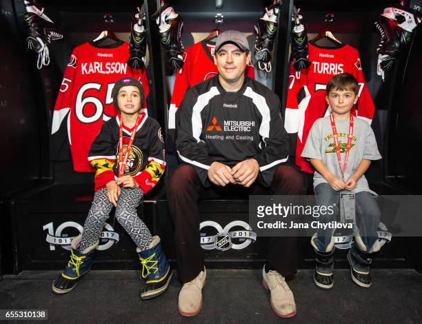 Former Ottawa Senators Chris Phillips poses for a photo with young fans in the locker room installation of NHL Centennial Fan Arena Museum at the...