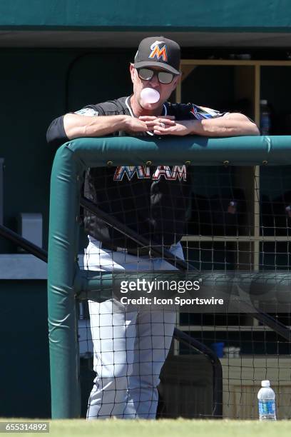 Marlins manager Don Mattingly watches the action on the field as he blows a bubble in the dugout during the spring training game between the Miami...