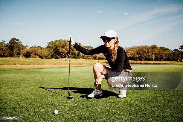 woman on golf course lining up her put - golf fotografías e im�ágenes de stock