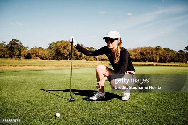 woman on golf course lining up her put - parcours photos et images de collection