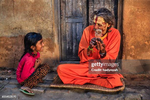 little girl observing how sadhu doing doing his makeup - daily life in nepal stock pictures, royalty-free photos & images