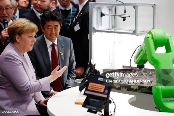 German Chancellor Angela Merkel and Japanese Prime Minister Shinzo Abe visit a booth with a robotic arm picking up sushis as they tour the Ce Bit...